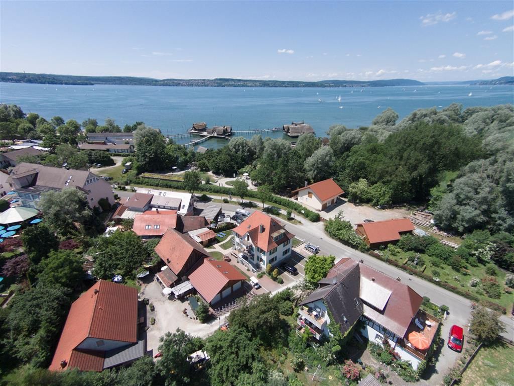 Luftbild von Unteruhldingen mit dem Haus Pfahlbaublick, dahinter der Bodensee